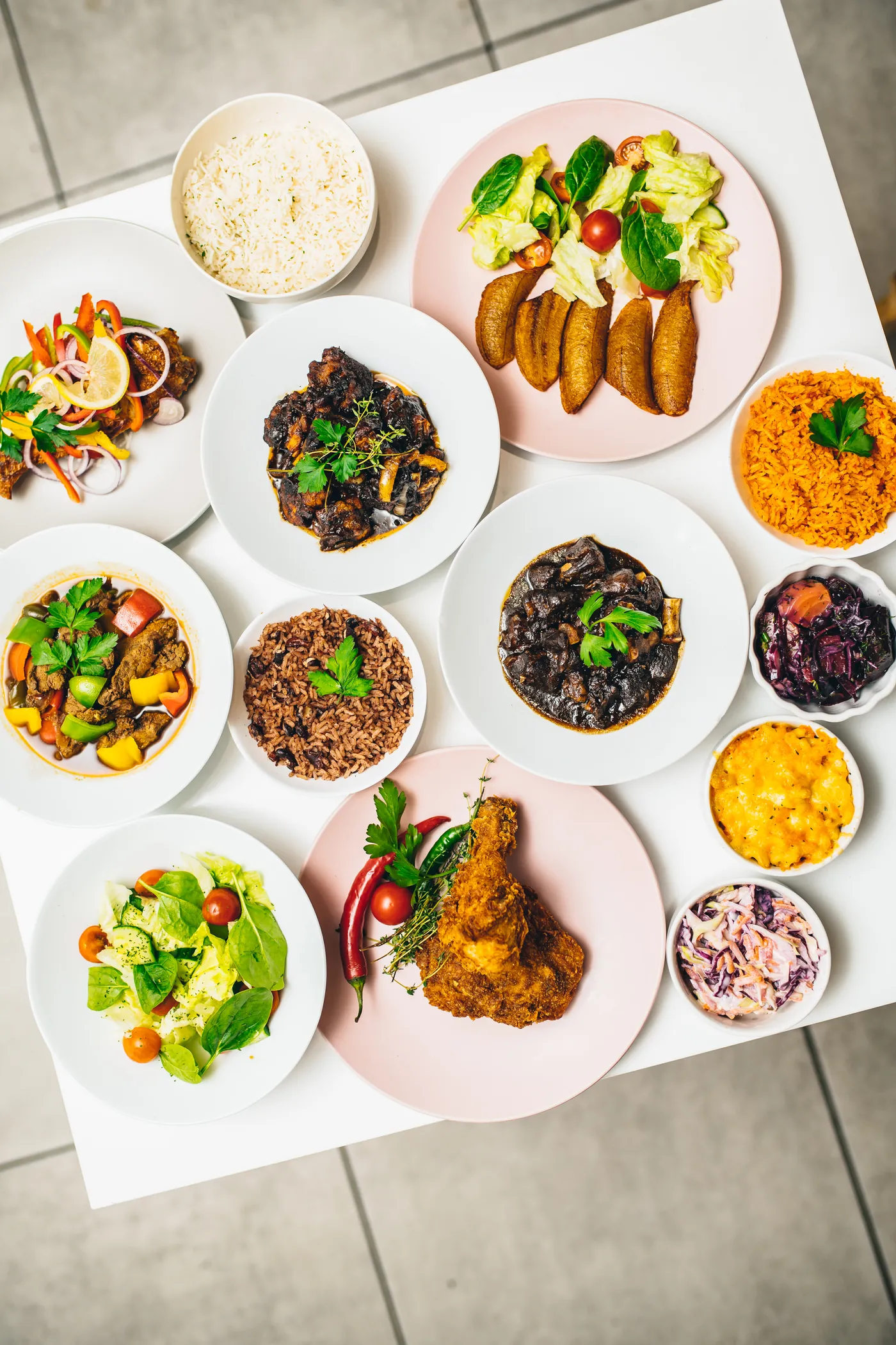 Afro-Caribbean catering spread by Tobis Private Catering London - curry goat, oxtail, jollof rice, rice and peas, fried plantain and mac and cheese